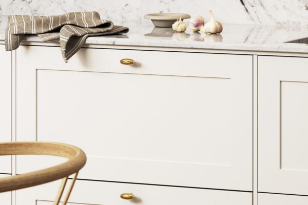 Detalj från platsbyggt kök med vit ramlucka, bänkskiva marmor och knopp Oliver i polerad mässing